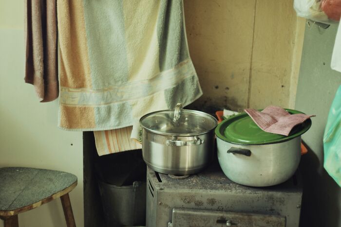 Old kitchen scene with pots on a stove, towels hanging, illustrating unexpected things witnessed in strangers’ homes.