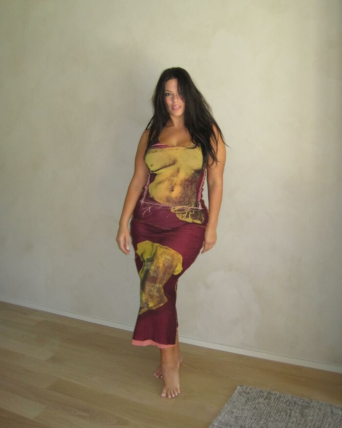 Woman in a patterned dress posing indoors, showcasing evolving beauty standards through history in a modern setting.