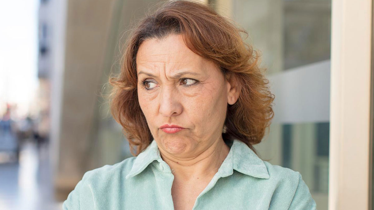 Middle-aged woman with a displeased expression standing outdoors, reflecting feelings of aunt ignoring nephew until he works