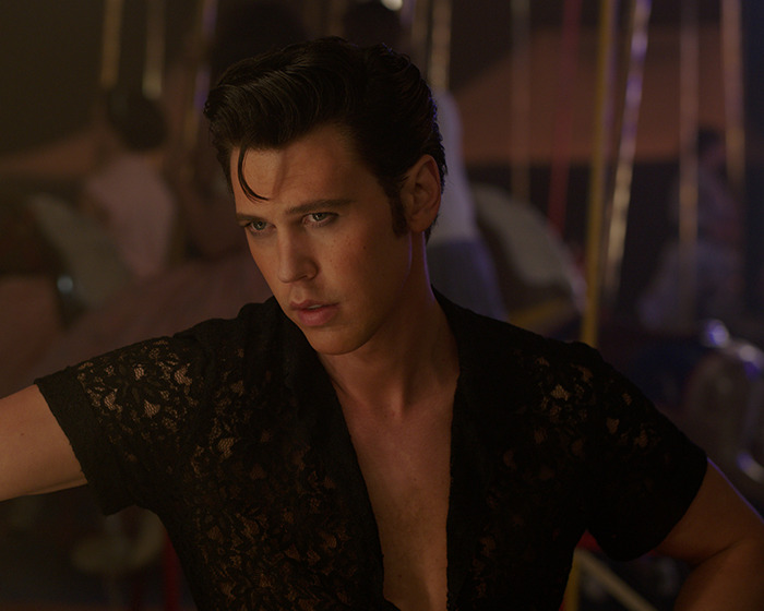 Austin Butler in a dimly lit setting wearing a black lace shirt, showcasing a peak male body look. Austin Butler in a dimly lit setting wearing a black lace shirt, showcasing a peak male body look.
