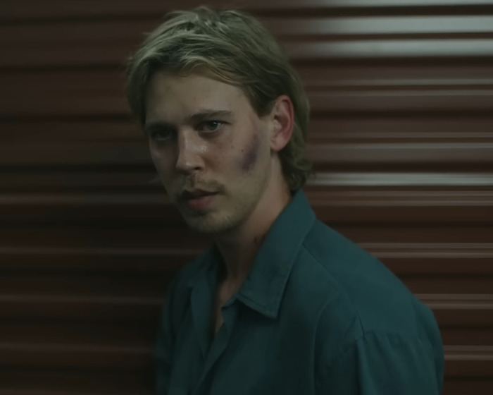 Young man with bruises on his face, wearing a dark shirt, posing against a brown striped background in dim light, peak male body. Young man with bruises on his face, wearing a dark shirt, posing against a brown striped background in dim light, peak male body.
