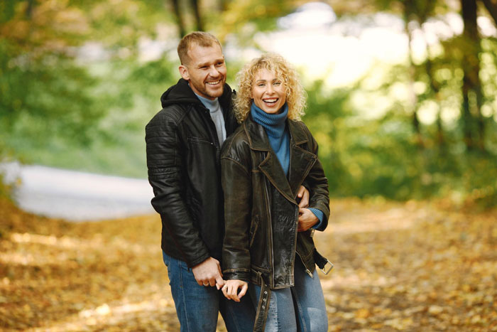 Couple walking in autumn park, smiling and enjoying the outdoors, illustrating parents obsessed with having kids. Couple walking in autumn park, smiling and enjoying the outdoors, illustrating parents obsessed with having kids.