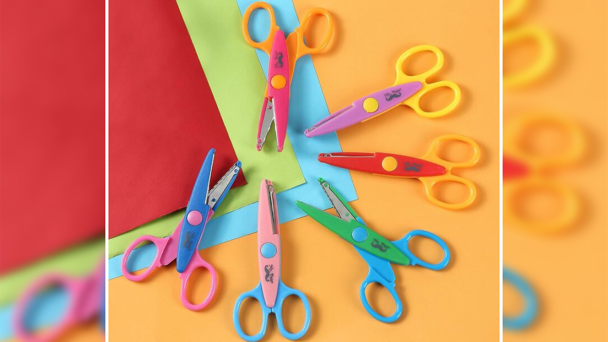 Colorful kids scissors arranged on multicolor paper sheets representing back to school finds for crafts.