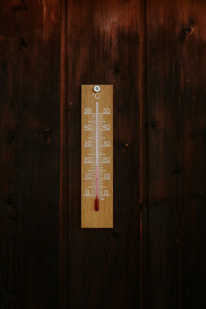 Thermometer mounted on dark wooden wall measuring temperature in Celsius, symbolizing PR campaigns and decisions fails.
