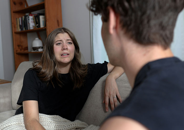 Woman faces double heartbreak, emotional while revealing boyfriend’s true character after mother’s death in a living room setting.