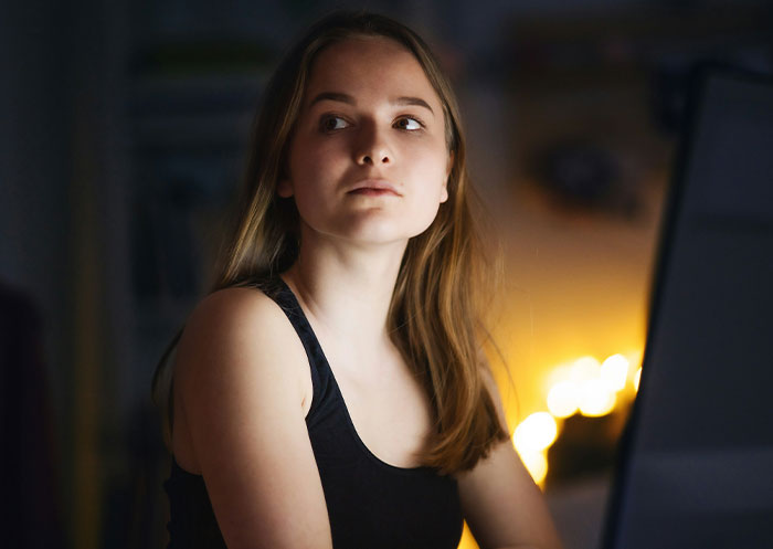 Young woman faces double heartbreak, reflecting on loss and boyfriend’s true character in a dimly lit room.