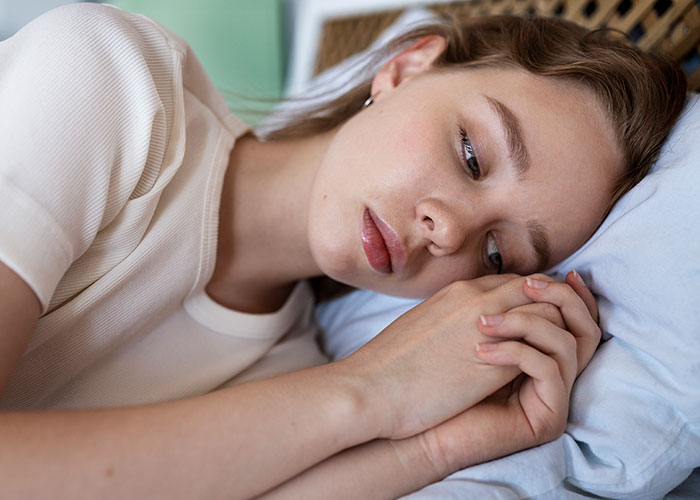 Young woman lying on bed, appearing thoughtful and distressed, reflecting on cancer related to HPV and relationship challenges. Young woman lying on bed, appearing thoughtful and distressed, reflecting on cancer related to HPV and relationship challenges.