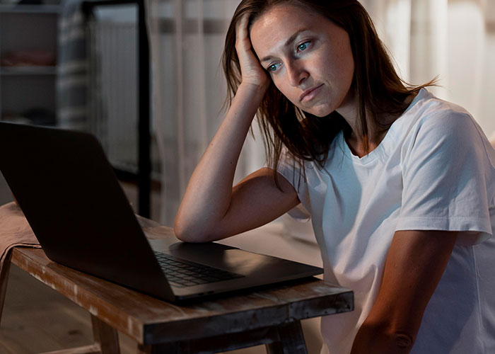 Woman with cancer feeling resentful while using laptop, reflecting on healthy boyfriend and past HPV diagnosis. Woman with cancer feeling resentful while using laptop, reflecting on healthy boyfriend and past HPV diagnosis.
