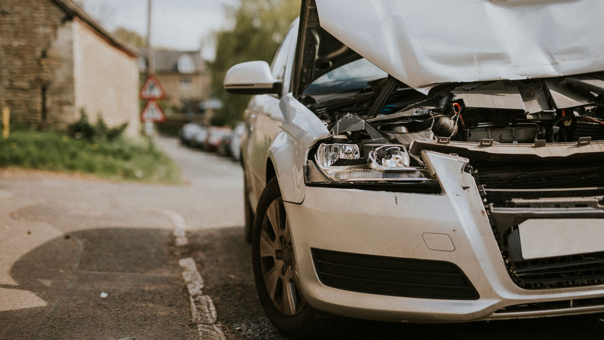 Damaged white car with a crumpled hood after an accident, illustrating chaos at a wedding crime scene.