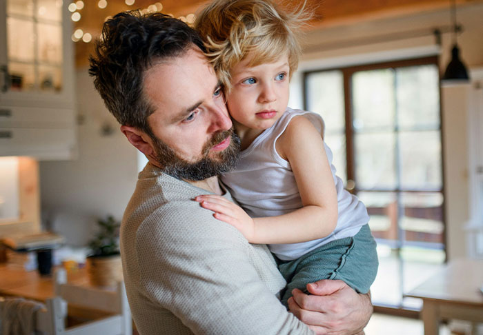 Man holding child indoors, illustrating a guy accusing sister of being a stranger to his kids after refusing childcare. Man holding child indoors, illustrating a guy accusing sister of being a stranger to his kids after refusing childcare.