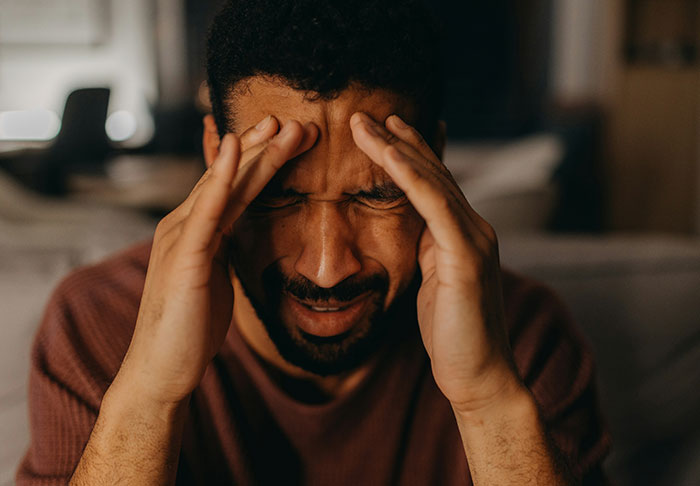 Man stressed and holding head in hands, illustrating conflict over sister refusing childcare duties and being stranger to kids. Man stressed and holding head in hands, illustrating conflict over sister refusing childcare duties and being stranger to kids.