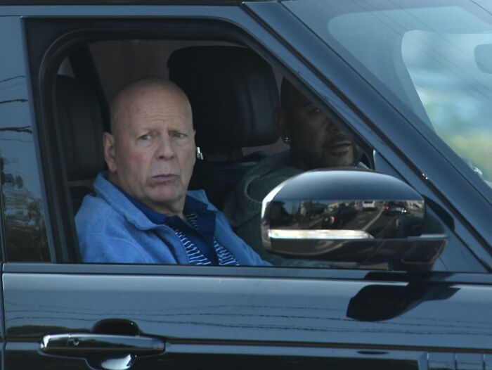 Bruce Willis sitting in a car with another man, highlighting his dementia battle and living separately update from his wife. Bruce Willis sitting in a car with another man, highlighting his dementia battle and living separately update from his wife.