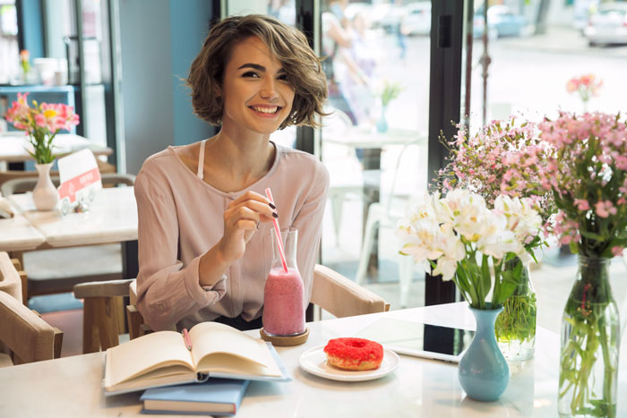 Young woman enjoying brunch with a smoothie and donut, prioritizing brunch date over dad’s surgery decision. Young woman enjoying brunch with a smoothie and donut, prioritizing brunch date over dad’s surgery decision.