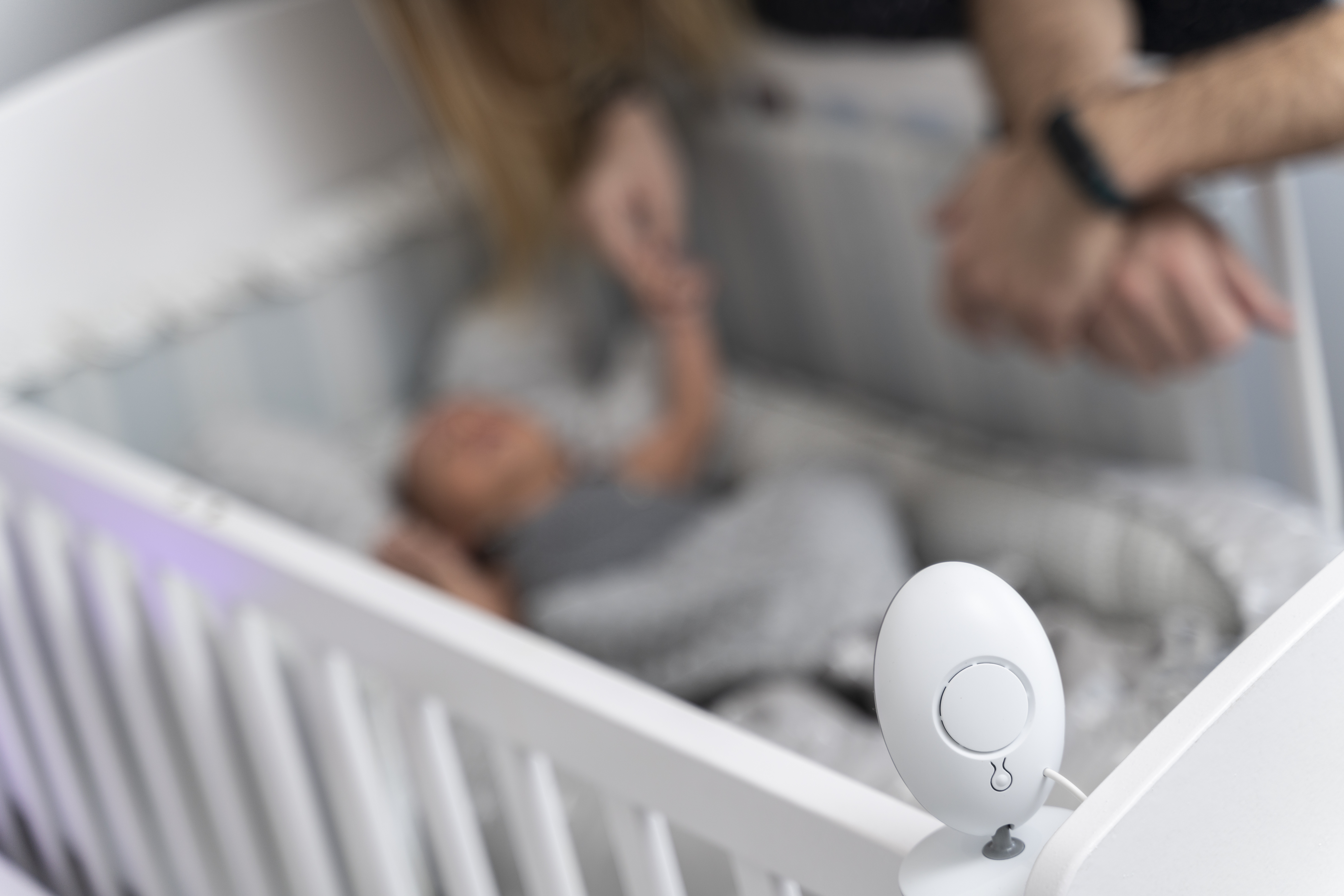 Baby monitor camera in focus on crib edge as mom watches over sleeping infant showing baby cam access concerns. Baby monitor camera in focus on crib edge as mom watches over sleeping infant showing baby cam access concerns.