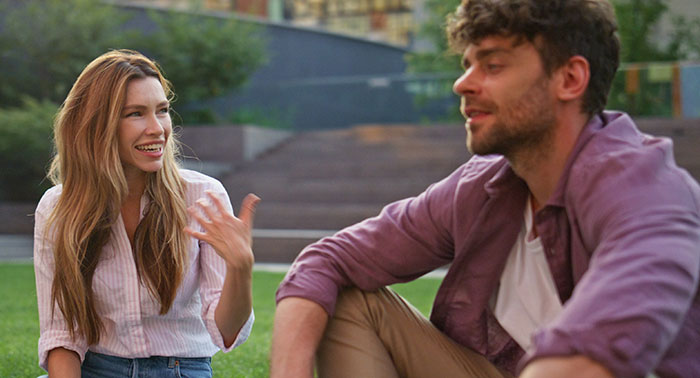 Two workers having an intense conversation outdoors, highlighting a gluten-free colleague issue at a pizza party.