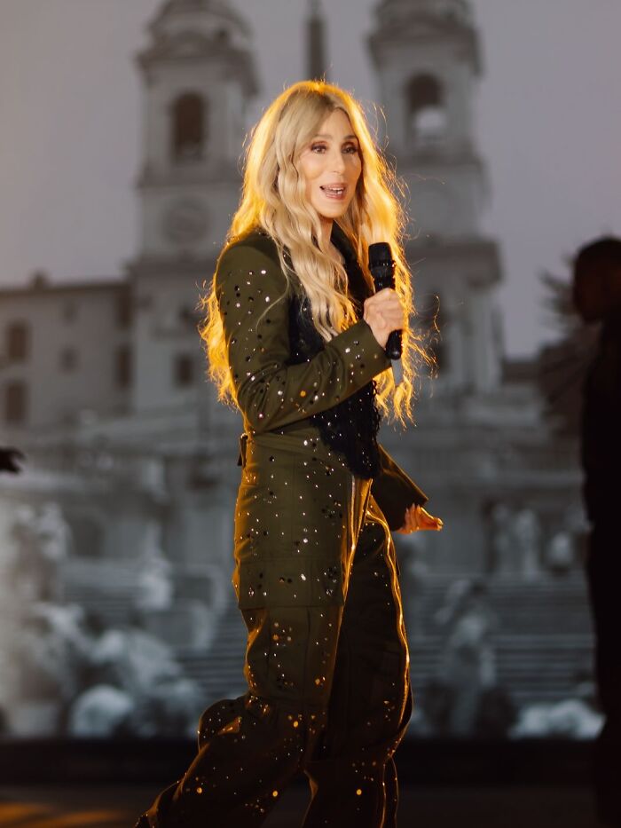 Cher performing on stage with long blonde hair, wearing a studded outfit amid concerns about her plastic surgery indulgence. Cher performing on stage with long blonde hair, wearing a studded outfit amid concerns about her plastic surgery indulgence.