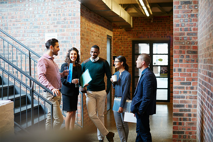 Group of diverse colleagues in a casual office setting discussing work and enjoying a lighthearted moment together. Group of diverse colleagues in a casual office setting discussing work and enjoying a lighthearted moment together.