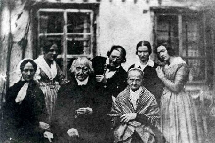 Black and white vintage photo of elderly people and women posing together illustrating concept time facts.