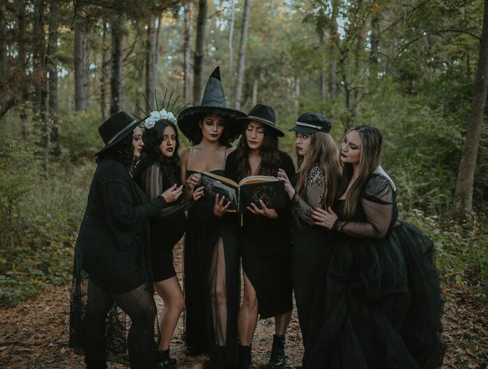 Group of women dressed as witches in the forest reading a mystical book exploring concept time facts.