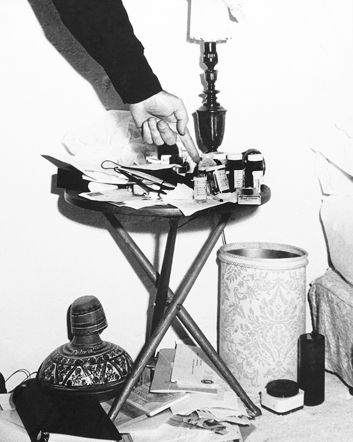 Hand pointing to prescription bottles on a cluttered table, related to Marilyn Monroe autopsy suspicious findings. Hand pointing to prescription bottles on a cluttered table, related to Marilyn Monroe autopsy suspicious findings.