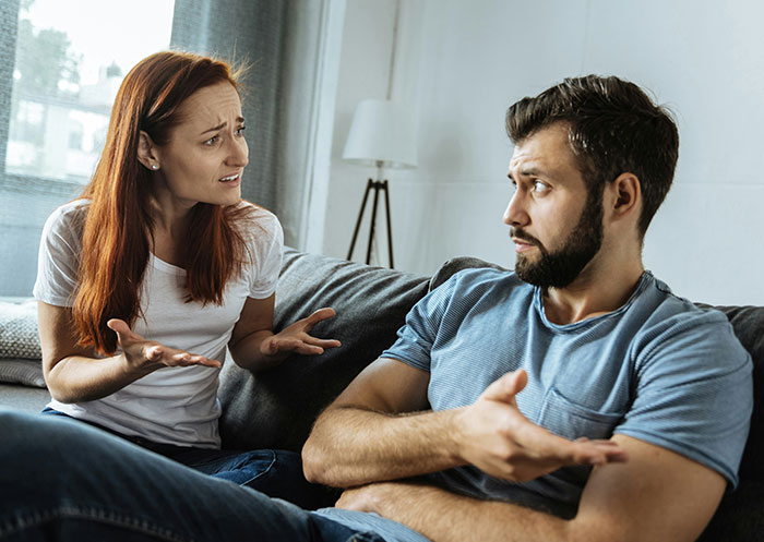 Couple having a serious conversation on a couch illustrating the ups and downs of a partner who went from rags to riches.