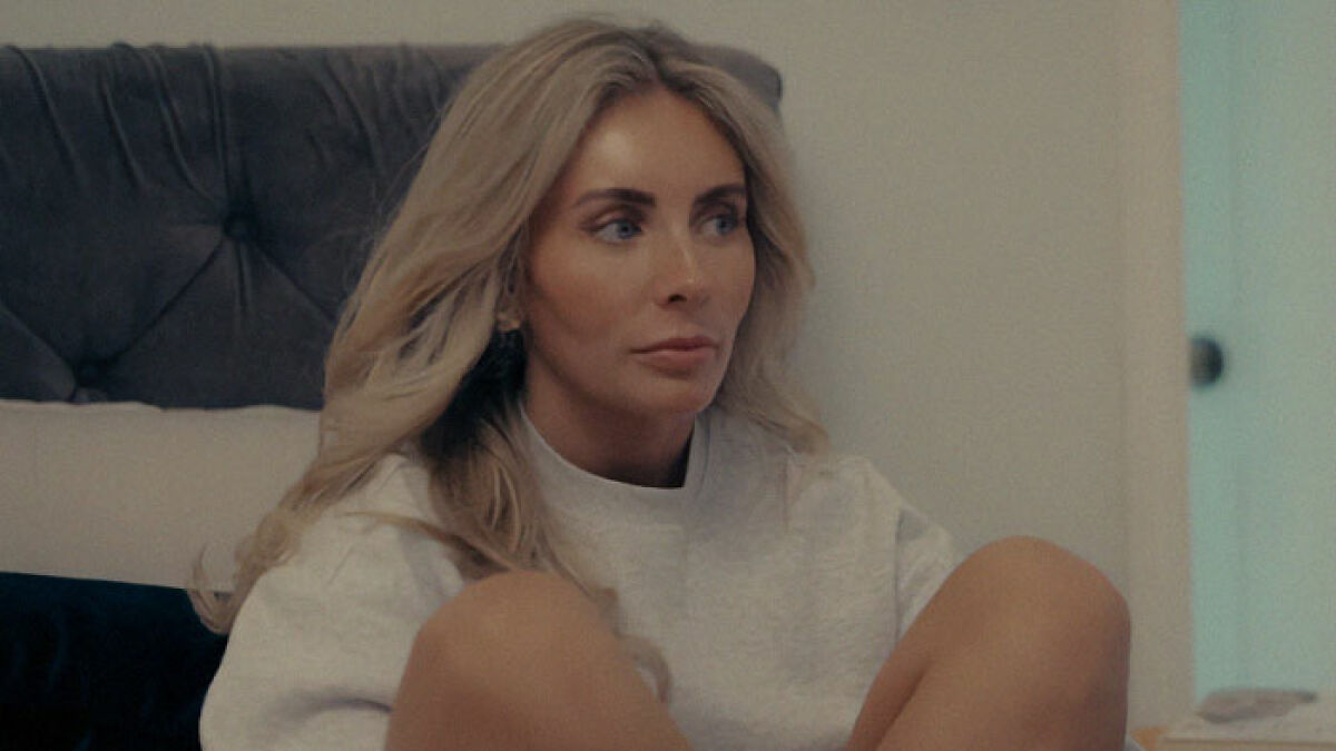 Woman with long blonde hair sitting indoors, body language expert decodes sudden expression change moment.