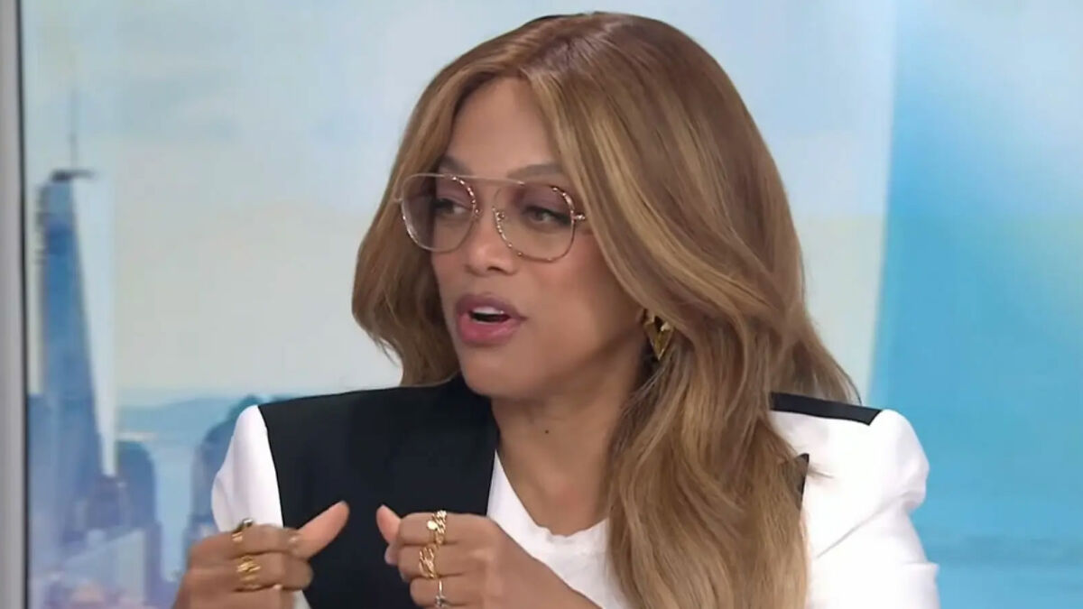 Tyra Banks speaking during an interview, wearing glasses and a black and white blazer, discussing an erotic fixation.