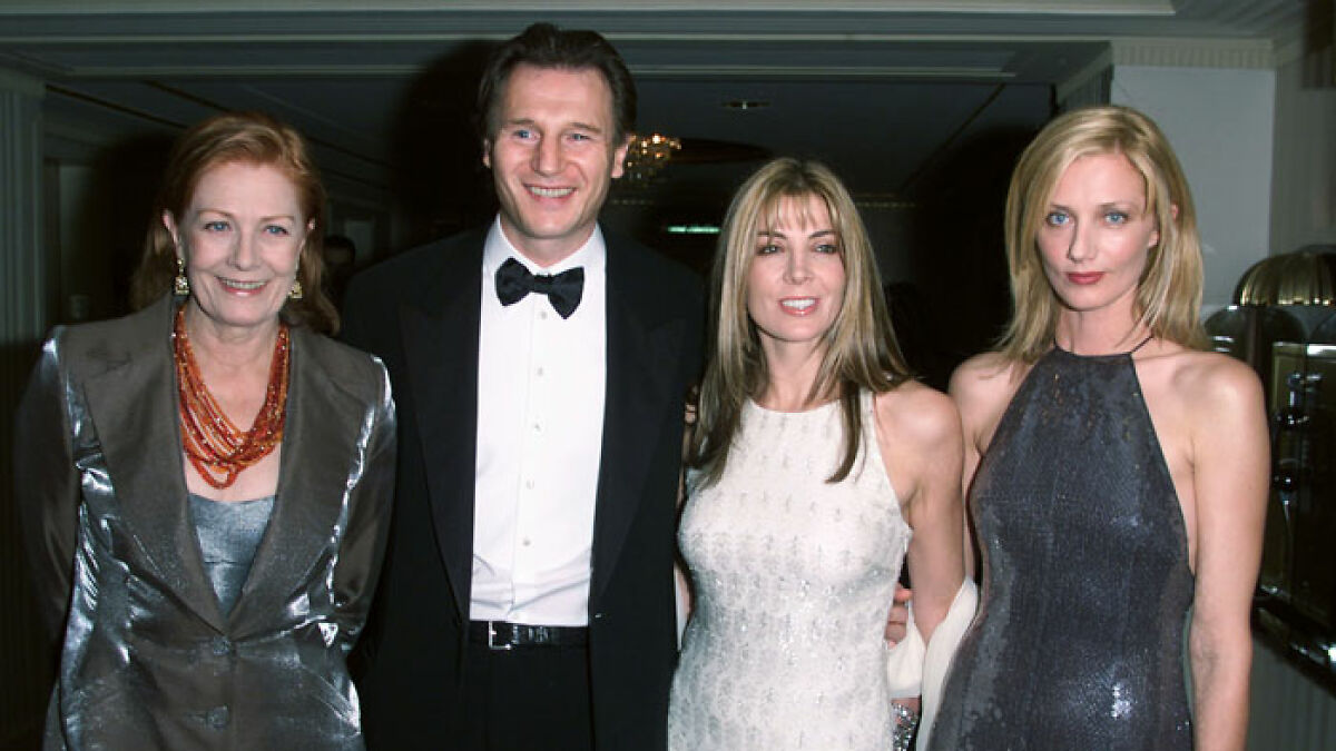 Liam Neeson in tuxedo with three women at a formal event, related to late wifeu2019s sister reaction to Pamela Anderson romance.