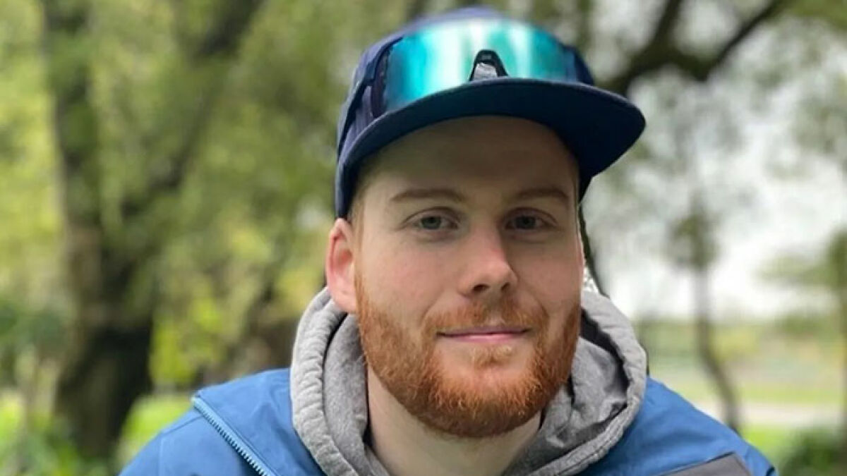 Young man wearing a blue cap and jacket outdoors, representing a good Samaritan protecting helpless mom and children.