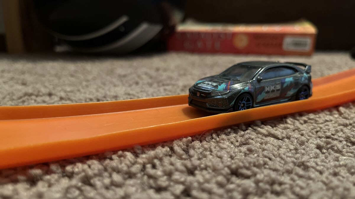 Close-up of a detailed diecast car on an orange Hot Wheels track as part of a diecast car collection display.