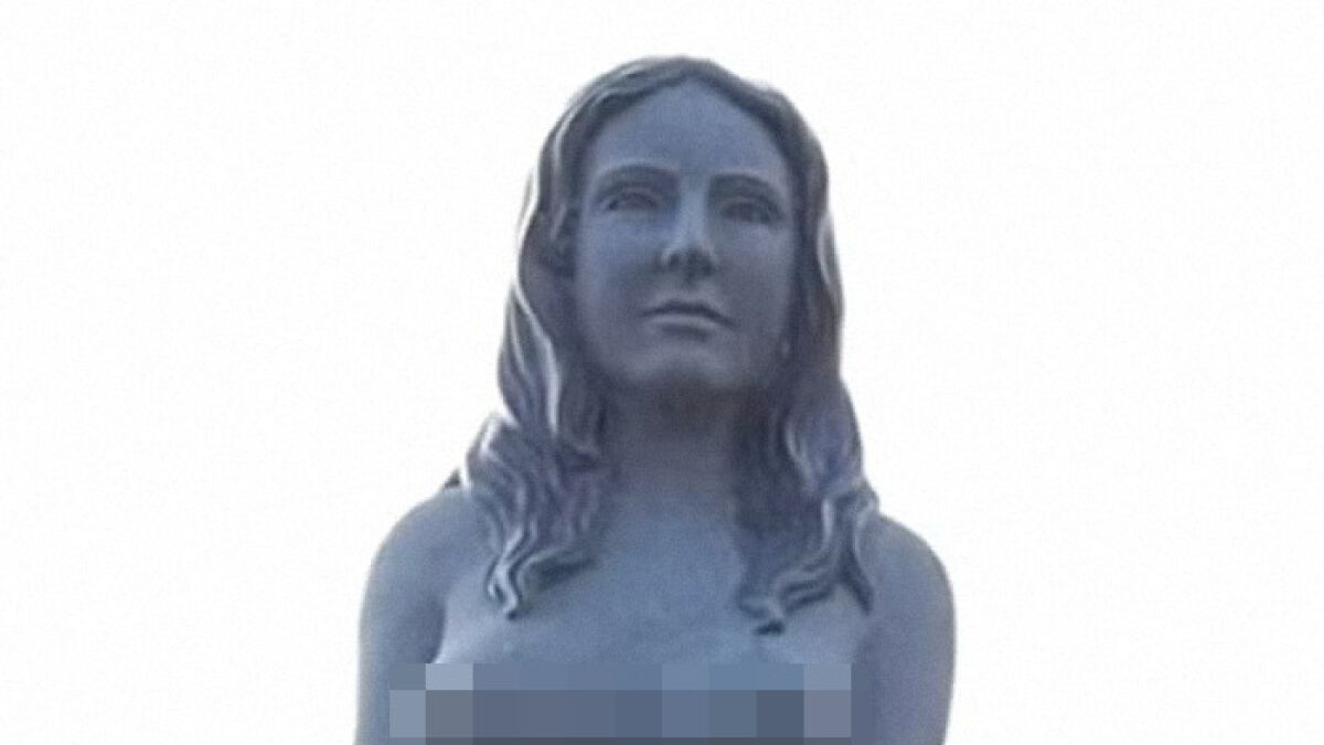 Statue of a famous mermaid with long hair, representing the female body, set against a plain white background.