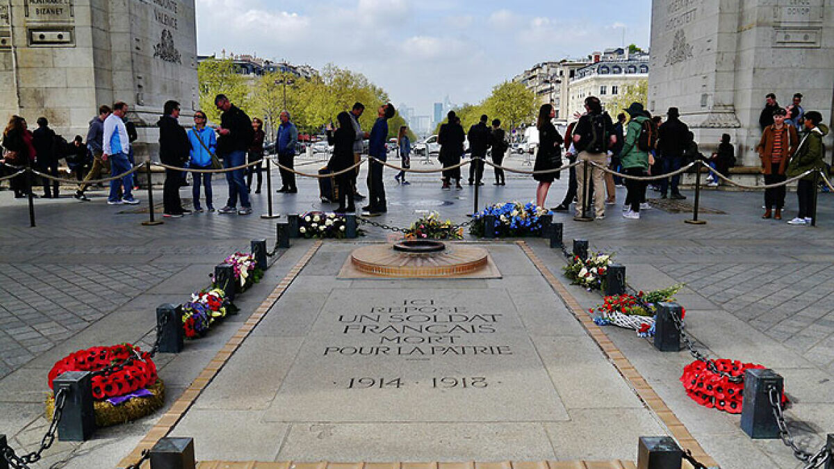 Crowd gathered near tomb of unknown soldier with flowers, symbolizing respect and memorial at historical monument site.