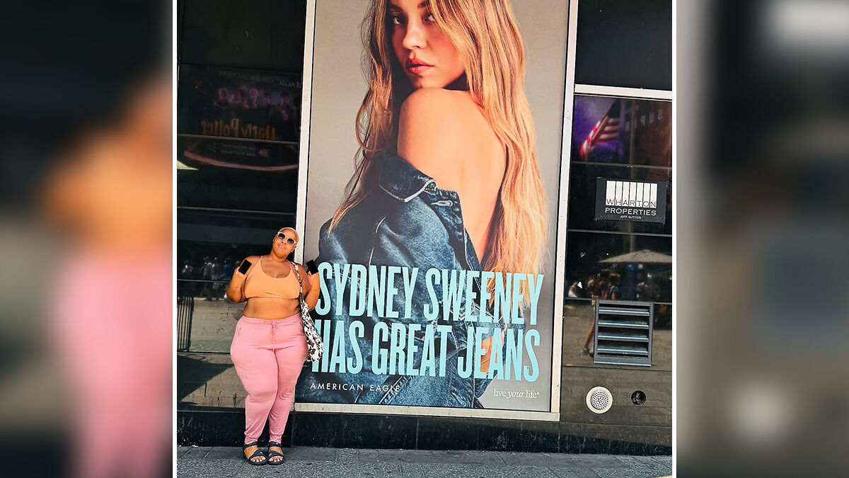 Influencer posing in front of Sydney Sweeney ad making a controversial gesture related to viral racist commentary post.