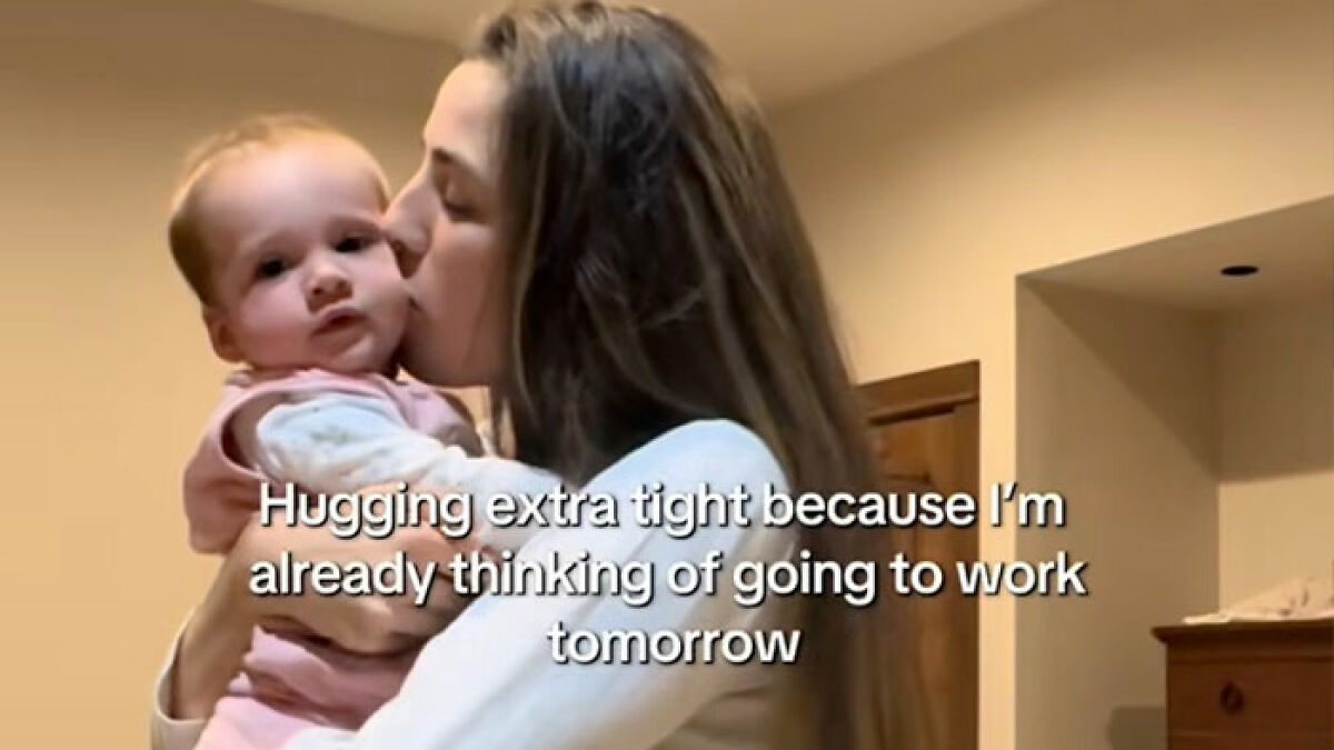 Woman cuddling baby, expressing the harsh realities of being a working mom in the U.S. with emotional intimacy.