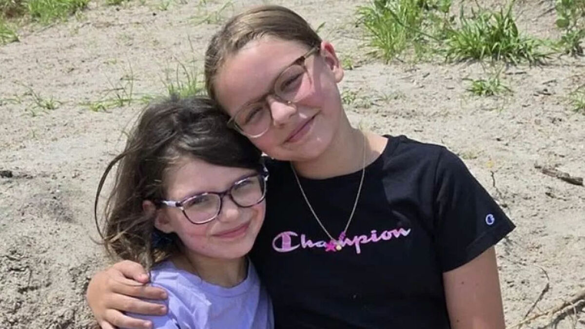 Two young girls with glasses smiling and hugging each other outdoors, related to heartbreaking final phone call before explosion.