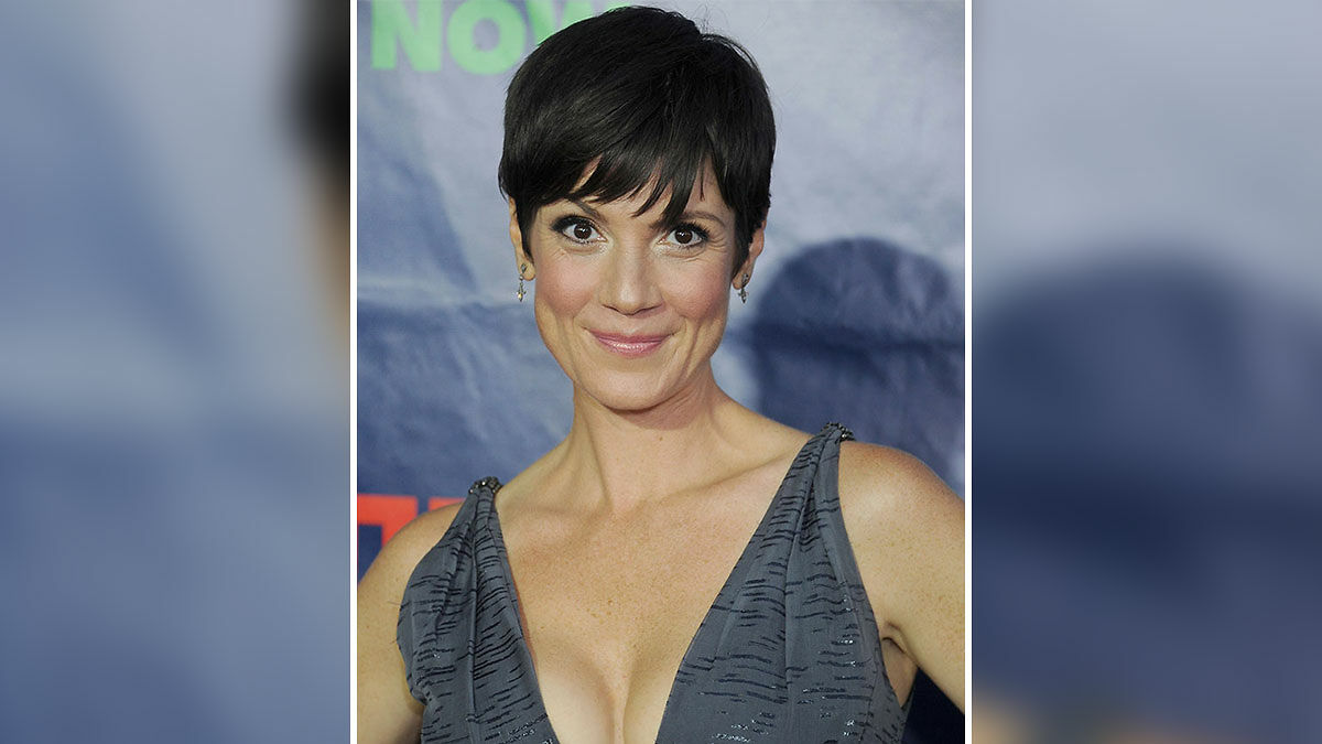 Female celebrity with short dark hair wearing a sleeveless gray dress at an event about unsolved disappearances.