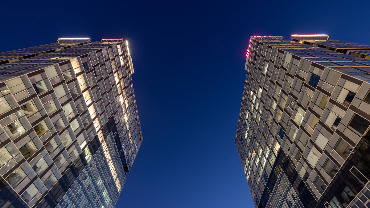 Two modern glass buildings lit at night under a clear sky showcasing architectural photography and industrial design.