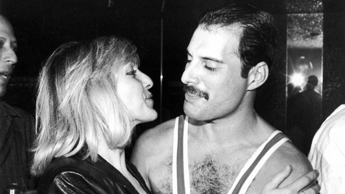 Freddie Mercury smiling and embracing a woman in a candid black and white photo, related to love child controversy.