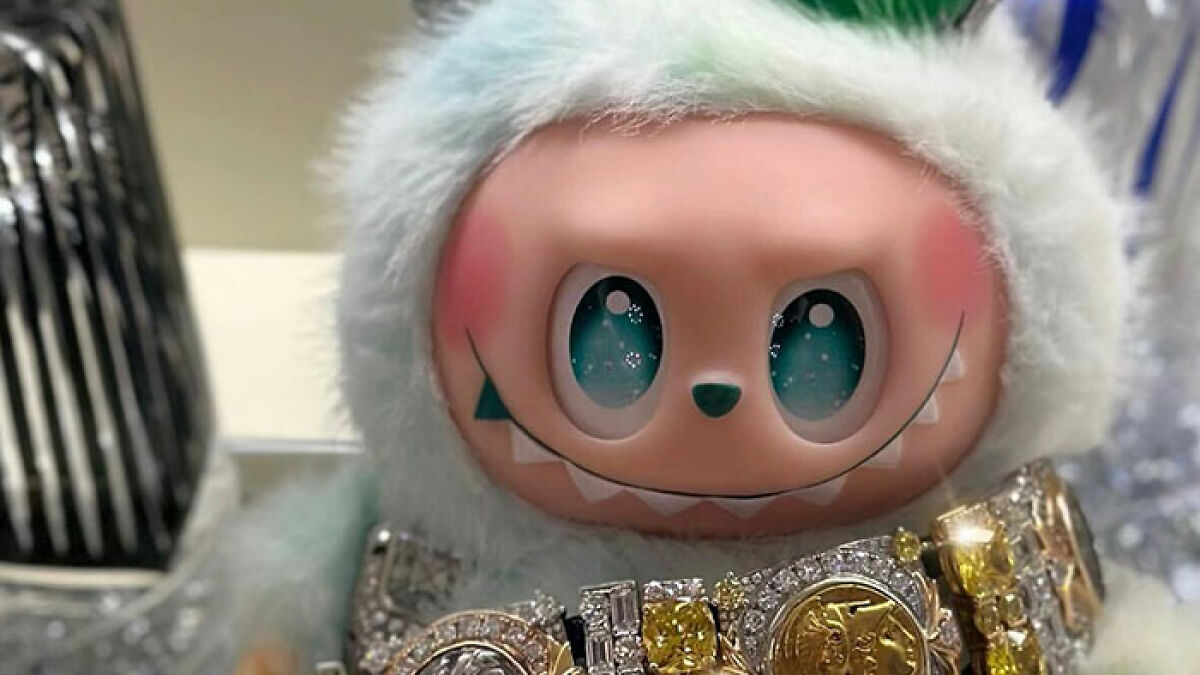 Close-up of a Labubu doll with sparkling eyes wearing a fluffy hood and adorned with a jeweled glass chandelier accessory.