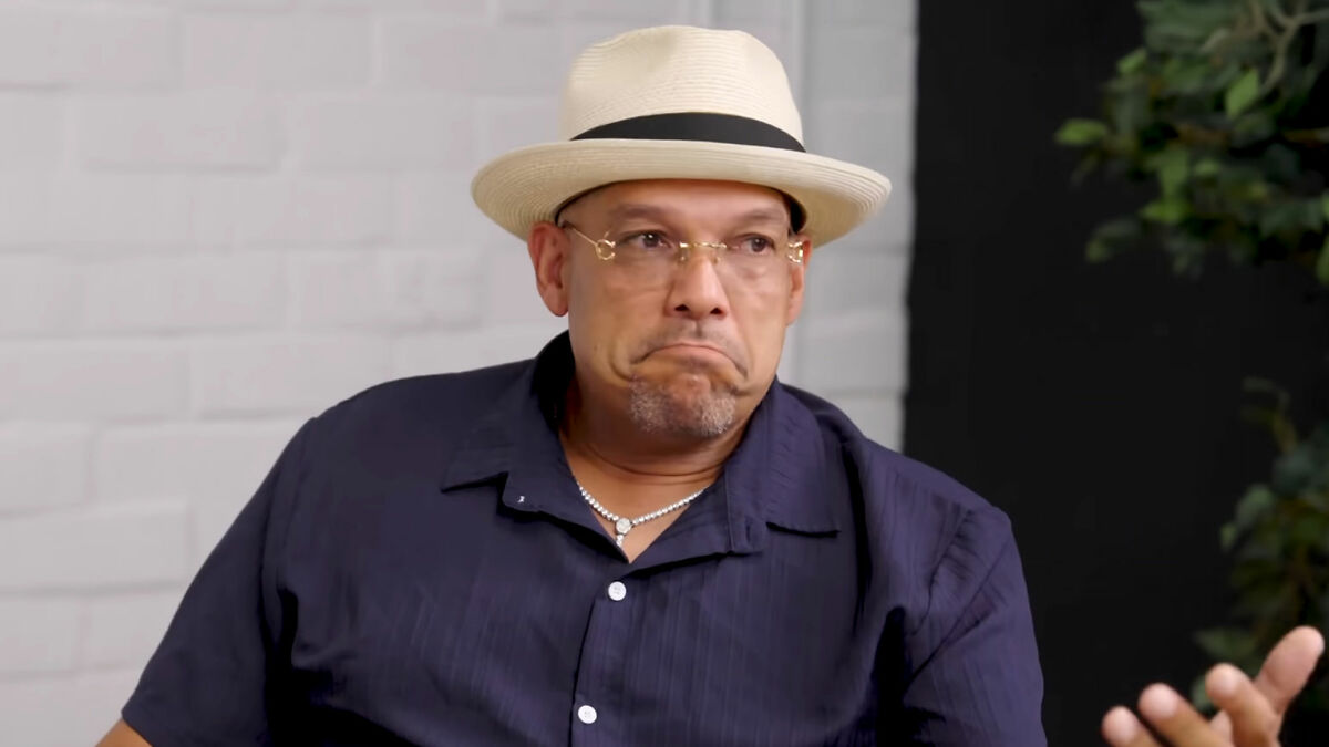 Man wearing a hat and glasses in an interview setting discussing Halle Berry's ex-husband claims and criticism.