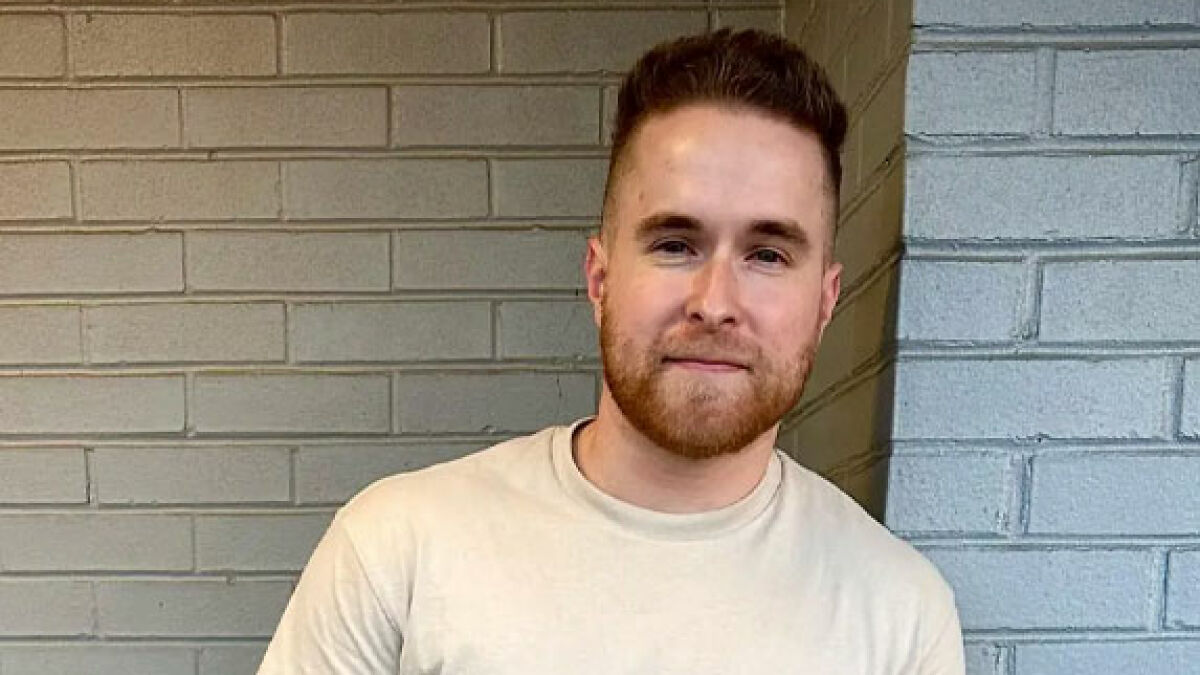 Young man smiling confidently against brick wall background representing short king height preferences in dating debates