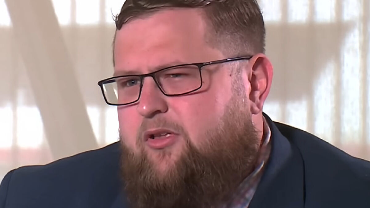 Man with glasses and beard speaking in an interview about plans if he is brother's biological father.