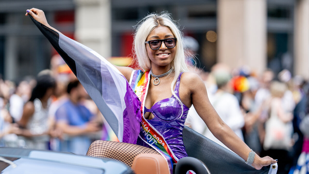 Person smiling at a pride parade holding a greyssexuality flag, representing the rise of greyssexuality in modern dating.