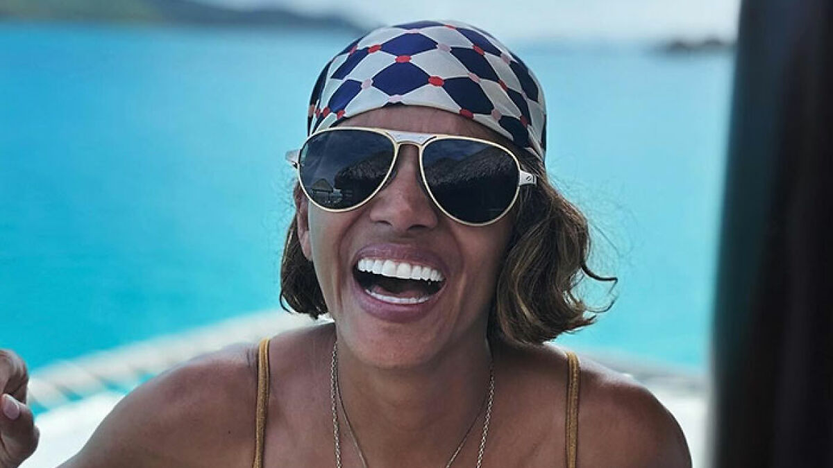 Halle Berry laughing outdoors wearing sunglasses and headscarf, reacting to ex-husband's cooking and cleaning claims.