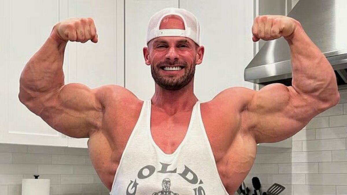 Joey Swoll flexing muscles in a white tank top and cap, applauded for takedown of men under 5 10 height claim