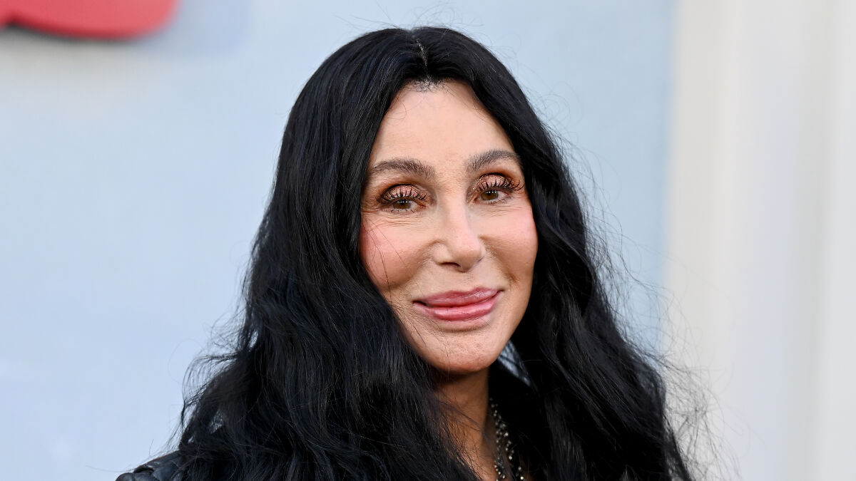 Cher with long black hair and makeup, sparking concern over her plastic surgery indulgence and melting appearance.