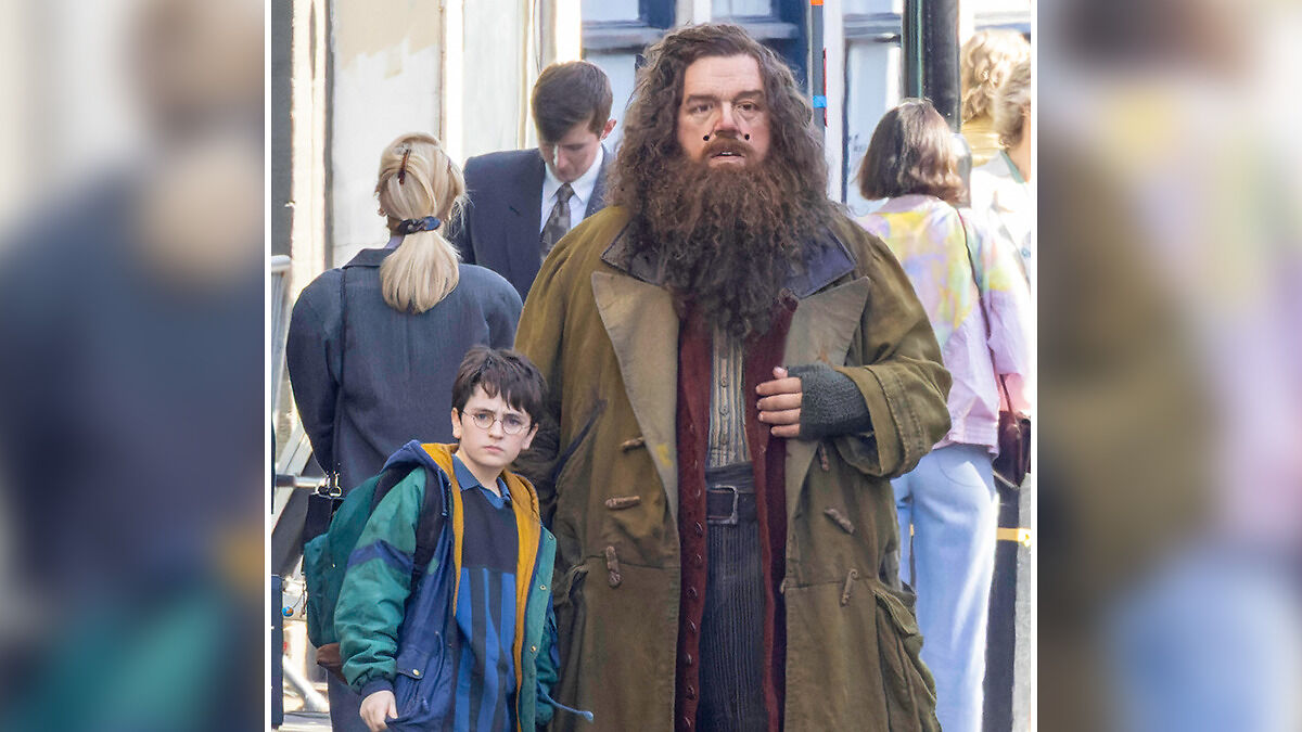 Actors in Harry Potter costumes on set, showing characters with a mix of casual clothing and fantasy attire in a street setting.