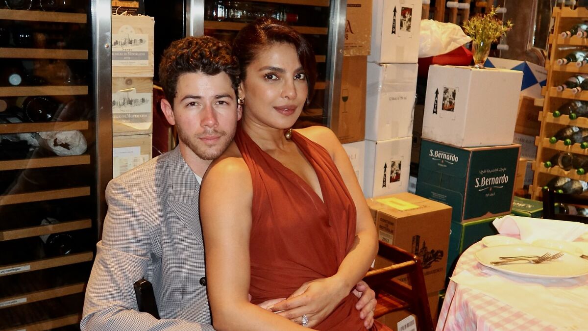 Nick Jonas and wife Priyanka Chopra posing together in a cozy setting, sparking debate about sitting in bed with spouse.