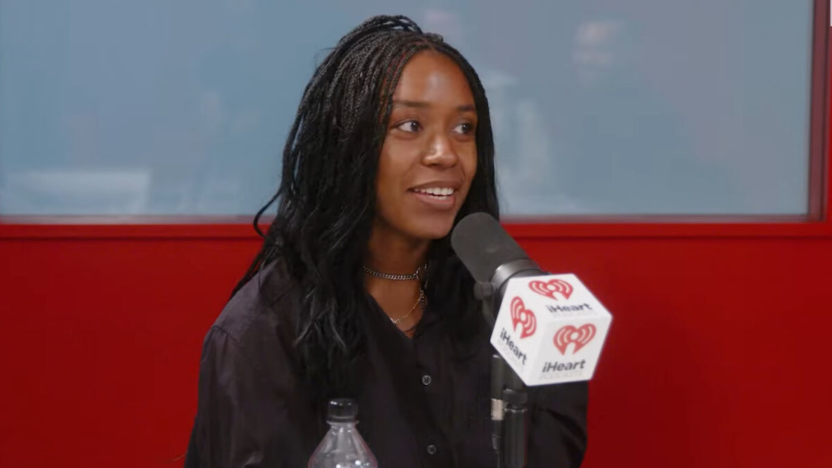 Woman speaking into a microphone during an iHeart radio interview about writer who trashed Sydney Sweeney controversy.