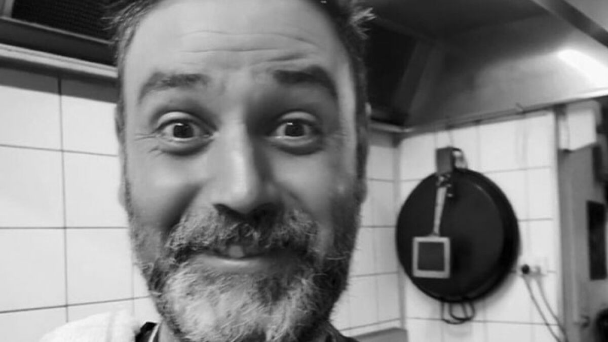 Cafu00e9 owner with beard in kitchen, addressing entitled customers after teen worker was left in tears.